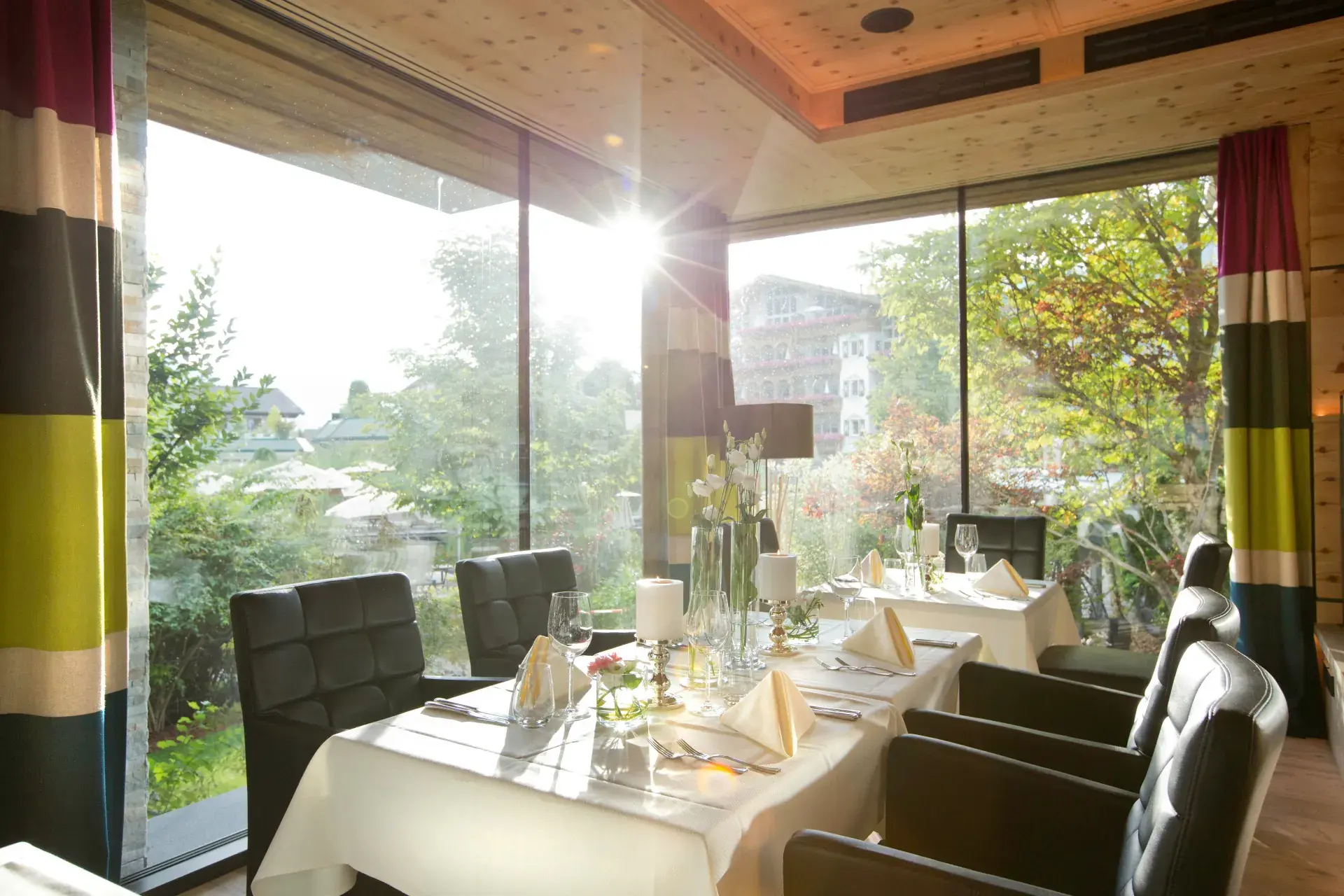 Lichtdurchflutetes Restaurant Zirbeneck im Greenvieh Chalet mit Zirbenholzdecke und eingedeckten Tischen